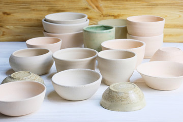 Fototapeta na wymiar Modern pottery. Decorative ceramic, clay plate. Handmade light pottery. Set of ceramic, bowls, cup with background.