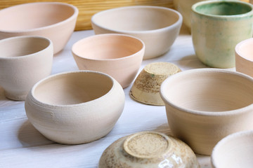 Modern pottery. Decorative ceramic, clay plate. Handmade light pottery.  Set of ceramic, bowls, cup with background.