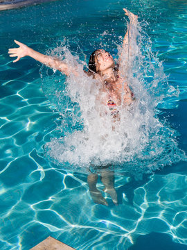 Young Woman Jumping Into The Swimming Pool