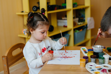 A boy and a girl play together and paint. Recreation and entertainment. Stay at home