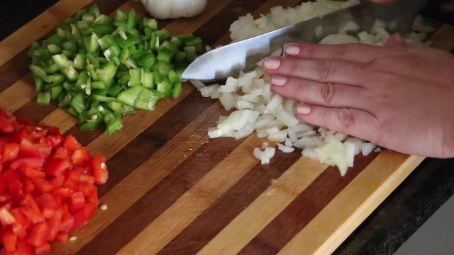 Cutting the vegetables, onions, green and red peppers into brunoise.