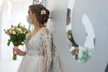 wedding and coronavirus covid 19-20. The bride in a protective medical mask, and a wedding dress,...