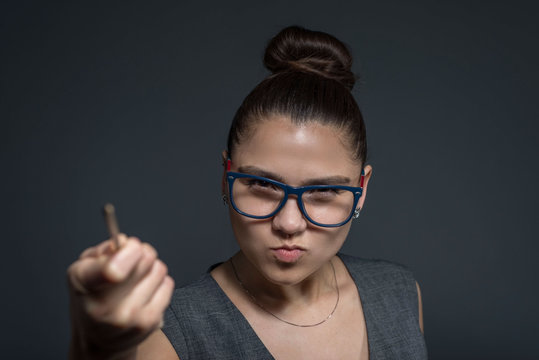close-up portrait of a brunette girl, strict teacher in glasses, looking at the camera, pointing with a pointer to the culprit. A strict young girl of twenty-seven years old