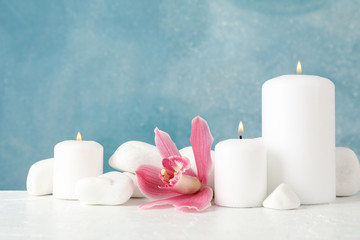 Beautiful orchid, candles and spa stones on white table, space for text