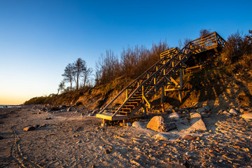 Fototapeta na wymiar Wooden stairs leading to the Baltic sea coast at Karkle beach , Klaipeda/Lithuania. Beautiful sunset view.
