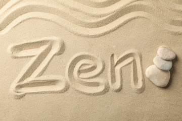 Inscription Zen and stones on sand background. Zen concept