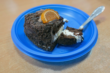 a piece of chocolate cake with white filling on a teaspoon on a blue plastic plate