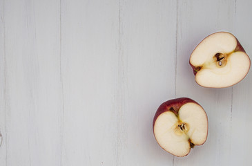 Two sliced apples on a white wooden surface, a table with copy space, top-down view, horizontal. The apples are located on the right side of the image