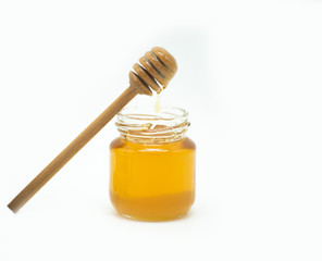 jar of honey with a spoon of honey on a white background