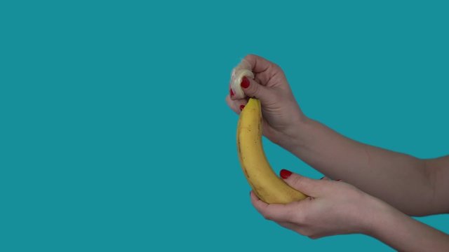 A condom is put on a banana. 4k Close-up. Blue background