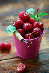 A bucket of cherries on a wooden table.
