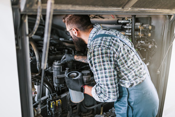 Bus maintenance worker checking oil level and filter condition