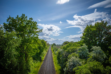 Railroad track lead straight to the horizon and the sky is blue