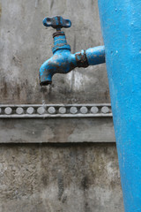 Blue column with water on a background of a gray wall.