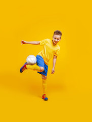 Fototapeta na wymiar boy plays soccer ball in studio on a yellow background