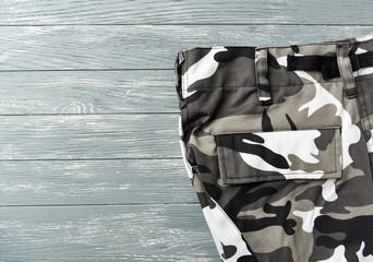 Trousers with a camouflage pattern on a wooden background. Top view. Copy space. 