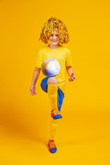 teen boy with a soccer ball and pompons for fans on his head