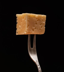 
a piece of cheese on a fork on a black background