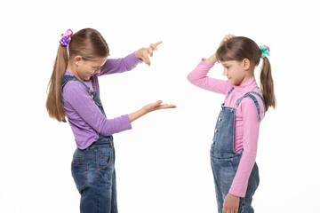 A girl shows a virtual object on her hand, another girl looks at her and scratches her head in...