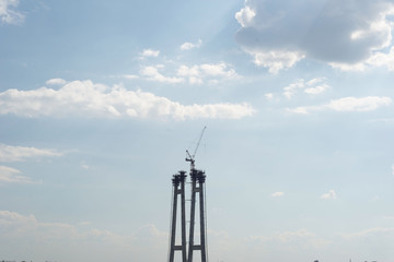 Obraz premium bridge structure in the city, against a background of green trees, and a cloud. The construction of a bridge in Ukraine, the city of Zaporozhye.
