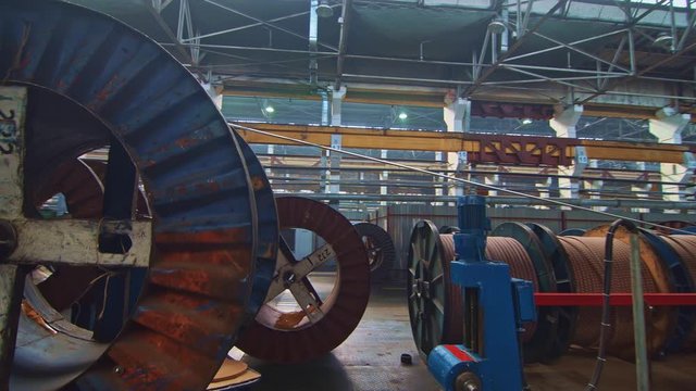 A huge bobbin unwinds a wire in a cable factory. Products are used in energy, transport, construction, engineering, nuclear, defense, oil and gas industries.