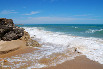 whipping waves against large stones on the shore