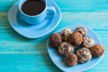 Energy balls on a plate and a Cup of coffee on a blue wooden table. Healthy homemade chocolate dessert for Breakfast will fill you with energy . Sprinkle nuts and cocoa