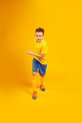 running boy in soccer uniform on a yellow background