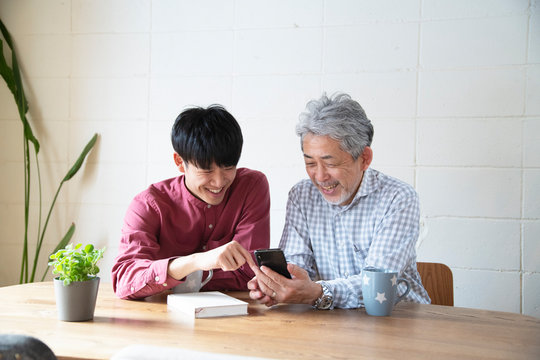 Senior instructed smartphone by young man