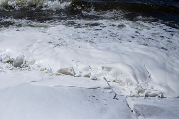 River bank, clear water and white thick foam from the surf.