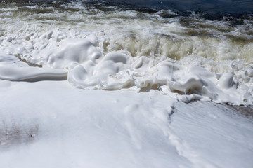 River bank, clear water and white thick foam from the surf.