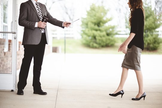 Man in suit handing out a church pamphlet to a woman