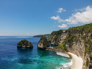 Obraz premium View of tropical beach, sea rocks and turquoise ocean, blue sky. Atuh beach, Nusa Penida island, Bali, Indonesia. Tropical background and travel concept