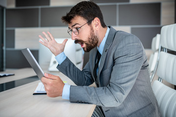 Businessman in shock of what hes seeing on his tablet screen
