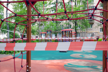 Fototapeta na wymiar The playground for sports in the yard of the house is closed and wrapped in a signal ingessofing coronavirus. Prevention of coronavirus COVID-19.