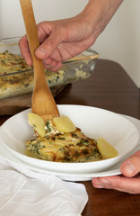 Woman serving healthy homemade potato gratin