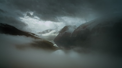 Wysokie szczyty górskie pokryte gęstą mgłą - obrazy, fototapety, plakaty