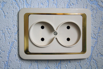 Double electrical outlet on a blue wall.