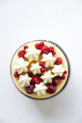 Individual cake with coconut and red berries. Decorated with chocolate, whipped ganache, berry coulis and berry caviar (agar). Cake is on a golden cardboard base, on a white background. Top view.
