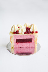The photo of the texture inside of a cake. Individual cake with coconut and red berries. Decorated with chocolate, whipped ganache, berry coulis and berry caviar (agar). White background. Back view.