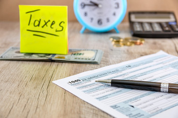Tax form 1040 with pen on the background of a calculator, alarm clock and money. "taxes" memo for 1040 individual tax forms. Financial document.