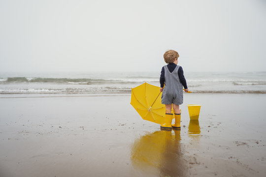 Boy standing on beach holding an umbrella, Bedford, Nova Scotia, Canada