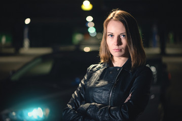 A young street racer woman is standing at night parking concept.
