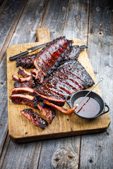 Barbecue veal spare loin ribs St Louis cut with hot honey chili marinade burnt as closeup on an old rustic wooden cutting board