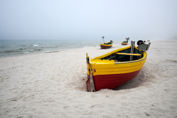 Naklejka na ściany i meble Fishing boats on the beach on a cloudy and foggy day. Baltic Sea, Poland