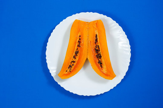 Tasty sweet sliced papaya fruit in a white bowl isolated on blue background
