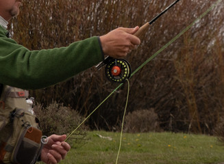A person casting a fly rod on a trout stream