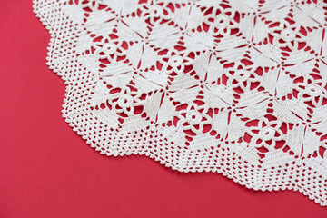 White handmade lace isolated on the red background. Crocheted accessory. Crafts and Hobbies for women. 