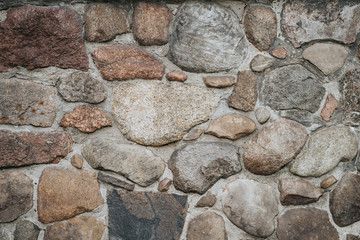 Background of a stone wall closeup. Texture of large and small multi-colored stones in concrete. Old rough concrete wall made of many stones
