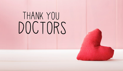 Thank You Doctors message with a red heart cushion over a pink wooden wall